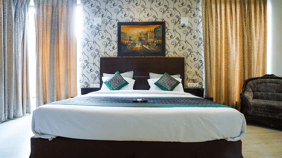 Guest room with a dark headboard, a framed Parisian Eiffel Tower painting, curtains, green cushions, and wall sconces.