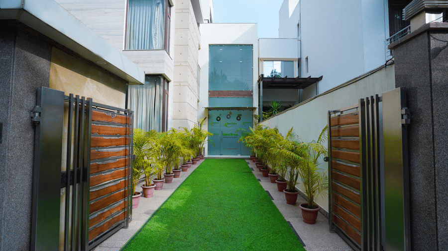 Modern hotel entrance with a landscaped walkway, manicured greenery, secure gates and contemporary architecture welcoming guests.