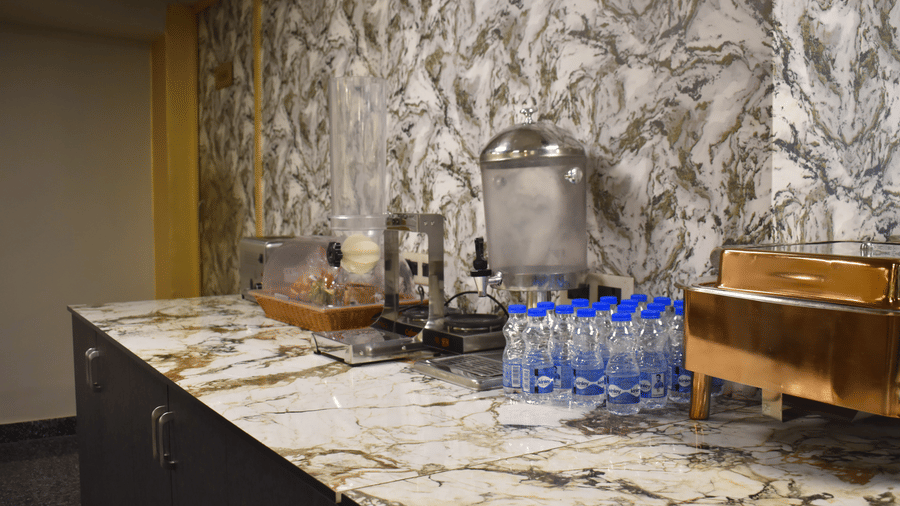 Refreshment counter featuring bottled water and a juice dispenser on a polished marble countertop.
