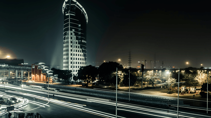 Night view of a skyline with illuminated buildings and city lights.