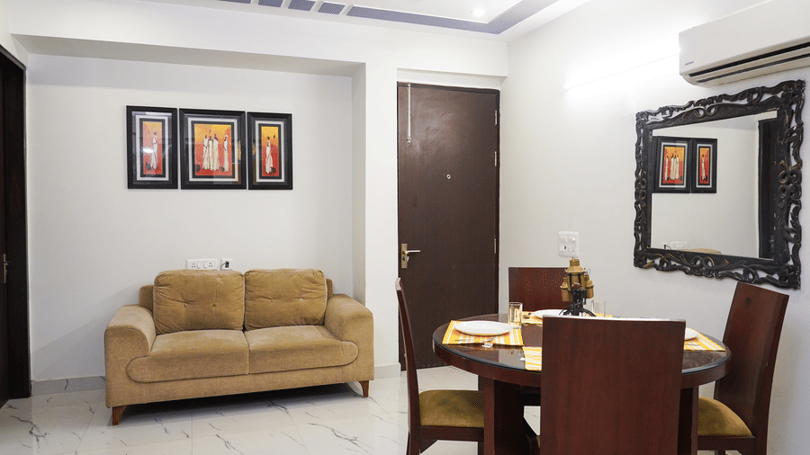 Suite of Lime Tree Hotels & Service Apartment Private Limited featuring a beige sofa, a dining table, and framed wall art.