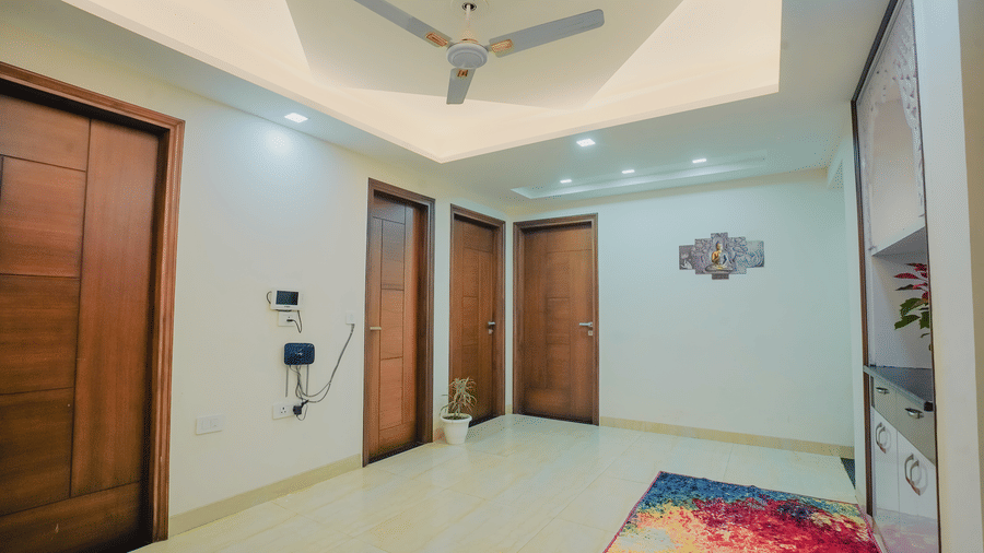 Corridor of Lime Tree Hotels & Service Apartment Private Limited featuring wooden doors and a colourful patterned rug.