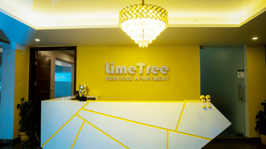 Reception desk of Lime Tree Hotels & Service Apartment Private Limited featuring a chandelier lit ceiling and a geometric patterned counter.