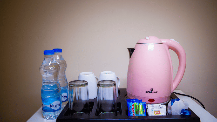Tea and coffee making tray featuring an electric kettle, glasses, and a water bottle.