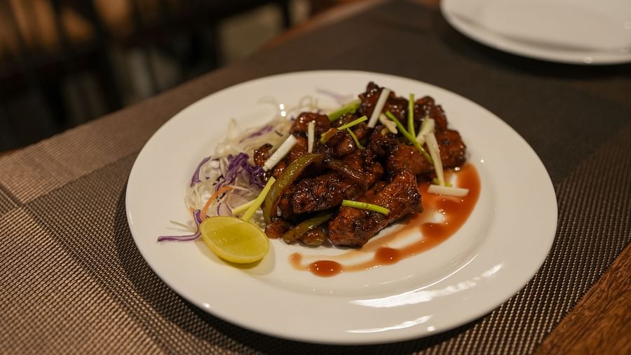 Plate of saucy fried starter garnished with spring onions, cabbage, and a lemon wedge at TGI Livancia Hillside, JC Nagar, Mysore