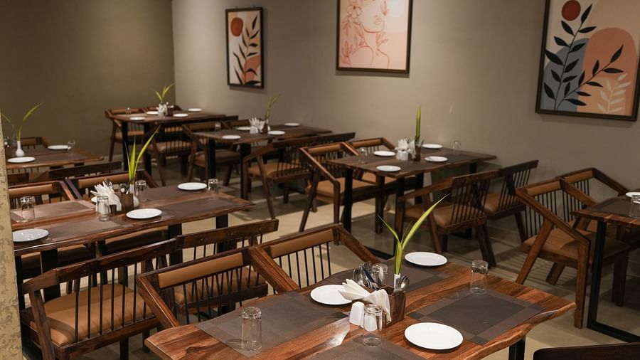Restaurant seating area with wall art and a focus on clean, minimalist table settings at TGI Livancia Hillside, JC Nagar, Mysore