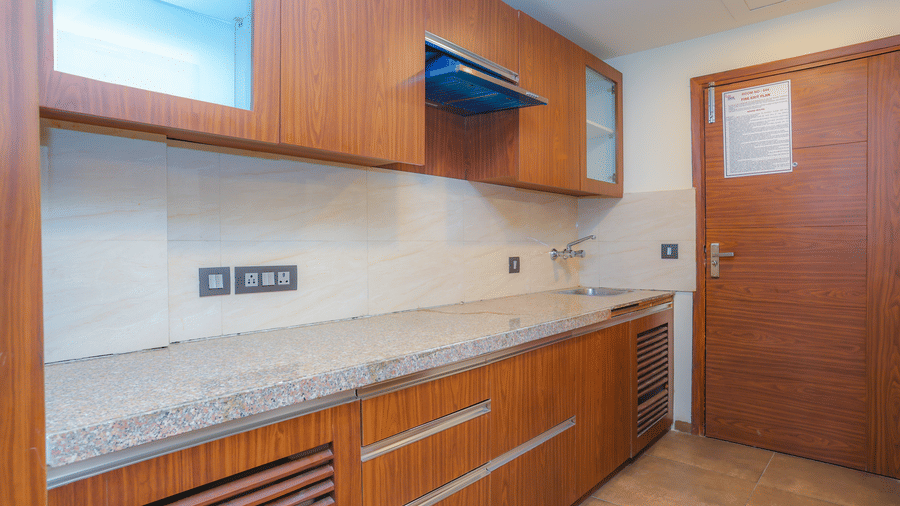 Kitchenette in the Premium Room with Balcony at Livbox, Dehradun, featuring a chimney, shelves, and wooden flooring.