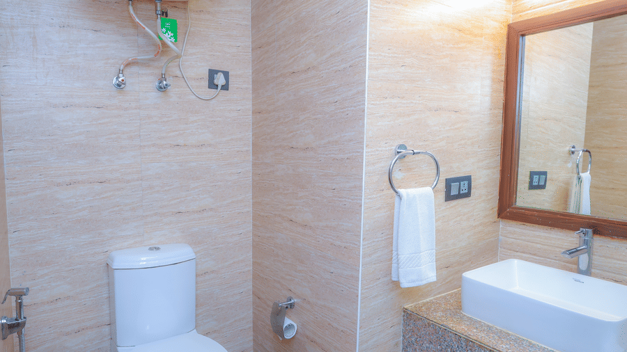 The western commode, sink, hand towel, and wall mounted heater in the bathroom of the accommodation at Premium Room with Balcony at Livbox, Dehradun.