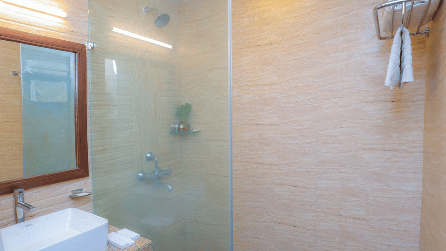 The separate shower area with glass partition in the bathroom of the accommodations at Livbox, Dehradun.