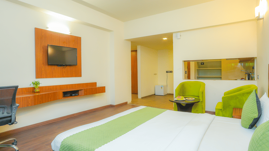 Corner view of the bedroom in the Suite With Balcony furnished with a king size bed, offering passage to the separate kitchen area - Livbox, Dehradun