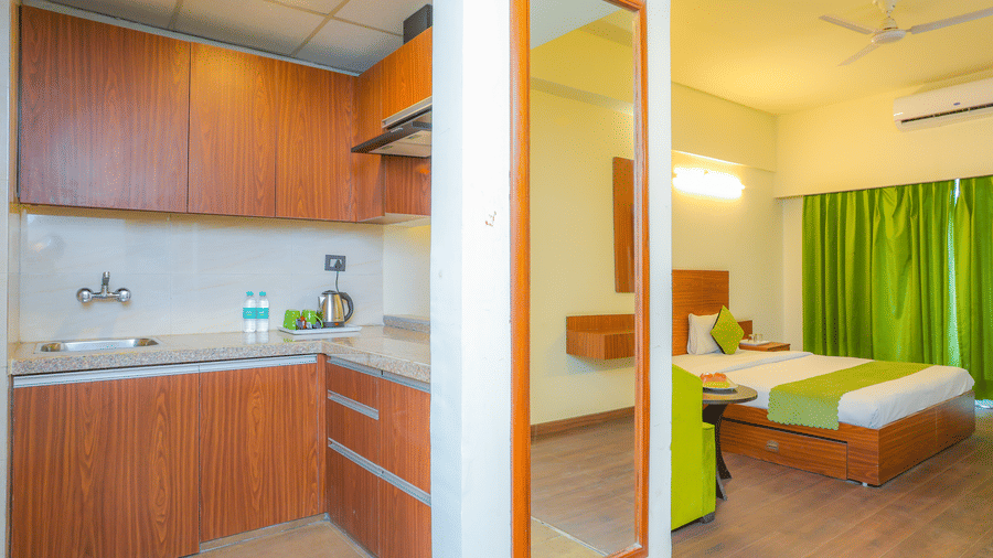 Suite With Balcony furnished with a separate kitchen, wooden flooring, king size bed, a wall-mounted mirror, and closed curtains.