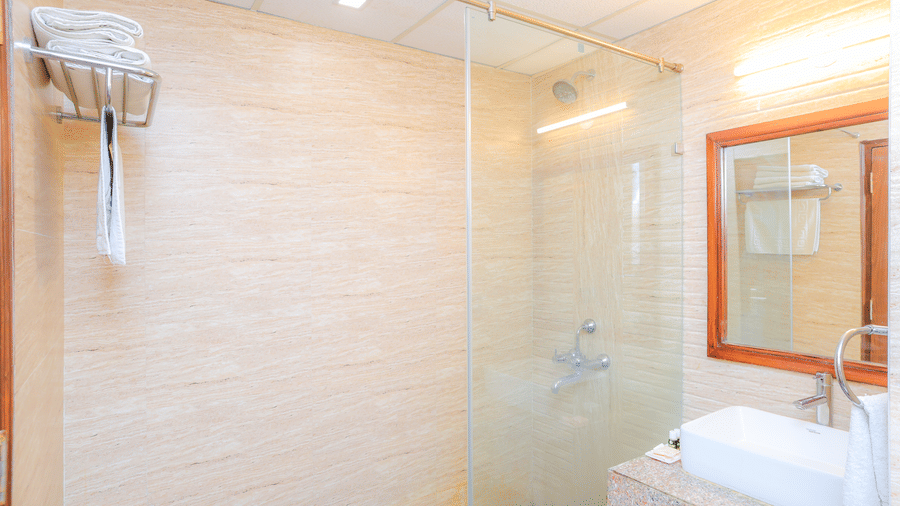 Towel racks and partitioned shower area in the bathroom of a Suite With Balcony at Livbox, Dehradun.