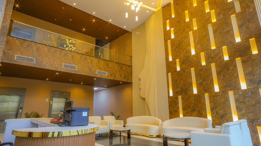The lobby area of Livbox, Dehradun, features a seating area with upholstered sofas, a multi-storey interior structure, and a grand patterned wall.