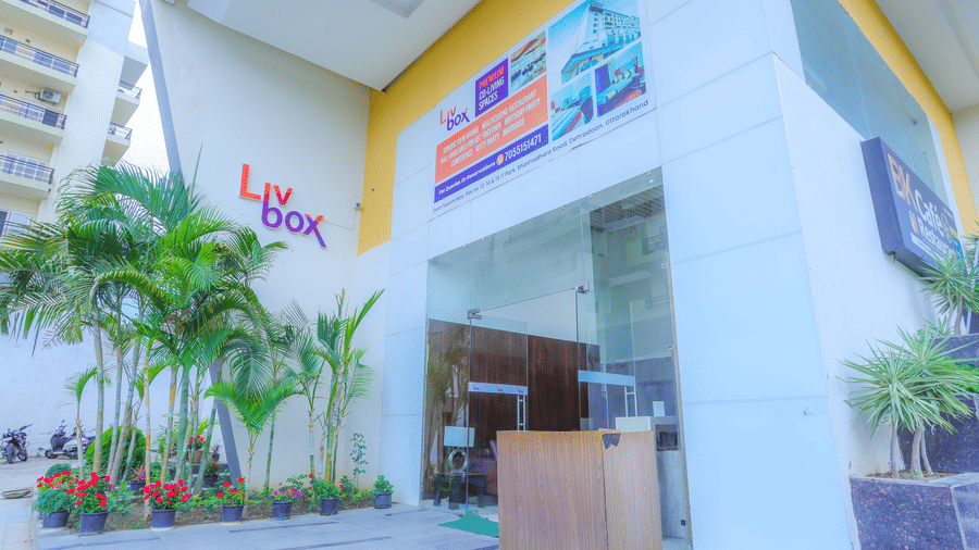 The facade of Livbox, Dehradun, featuring a large entrance, potted plants placed ahead of the entrance.