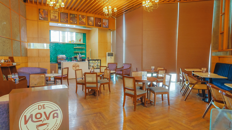 Warm cafe setting at Livbox Supernova with wooden flooring, modern tables, and natural lighting.