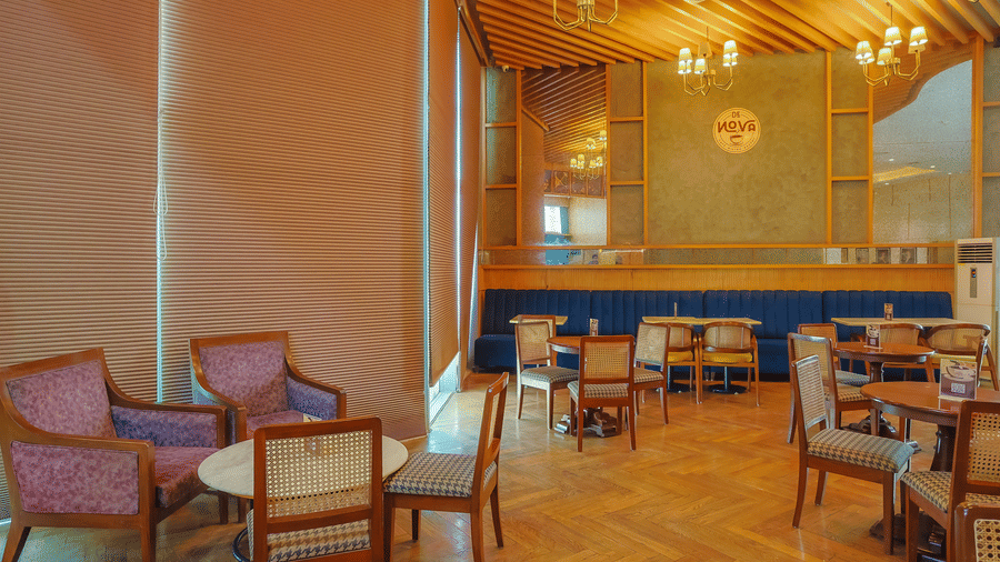 Restaurant space at Livbox Supernova, Noida, with neatly arranged tables, plush chairs, and an inviting ambience.
