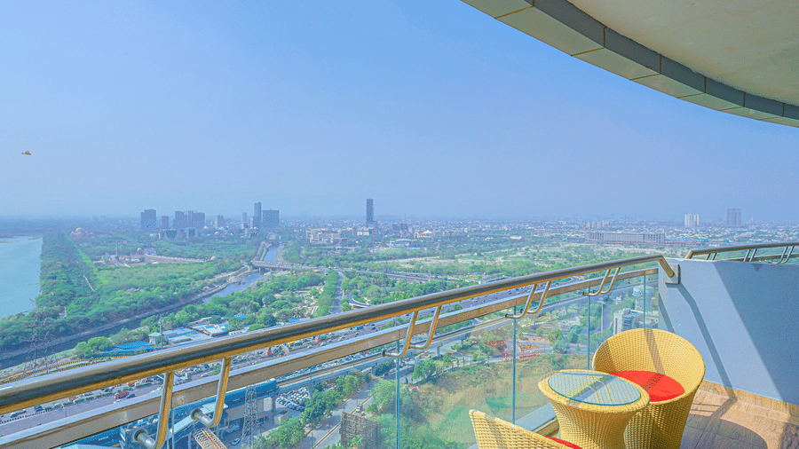 Private balcony with seating area overlooking the Yamuna River and Noida city skyline at Livbox Supernova, Noida.