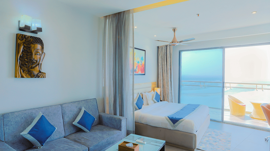 Cosy seating area with cushioned sofas and coffee table beside a balcony at Livbox Supernova, Noida.