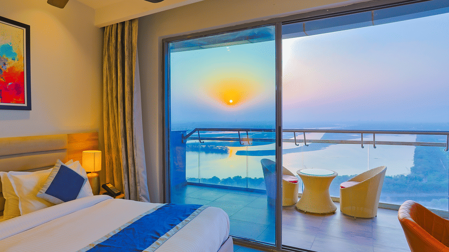 Bedroom with sliding glass doors opening to a balcony, showcasing a sunset view at Livbox Supernova, Noida.