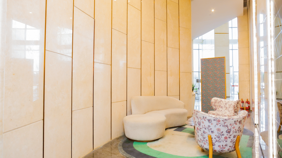 Lobby area of Livbox Supernova, Noida with white cushion sofa and elegant interiors with ambient lighting.