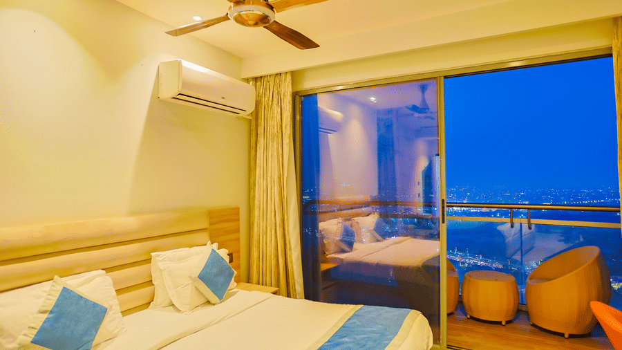 Cosy bedroom with king size bed and balcony seating at Livbox Supernova, Noida.