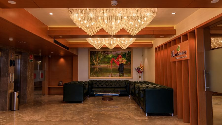 The warmly lit lobby of Lords Eco Inn Apple Gate features plush seating, artwork, distinctive chandeliers, and lift access.