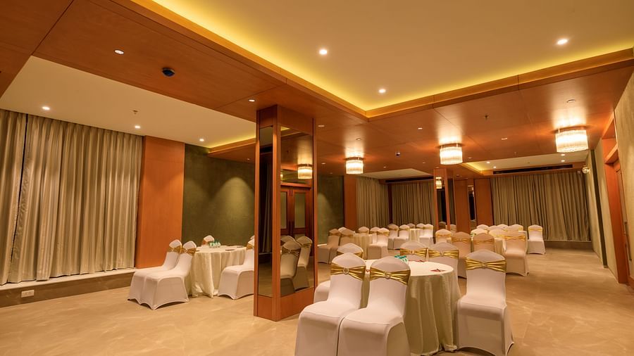 A softly lit function room at Lords Eco Inn Apple Gate is arranged with round tables and covered chairs, ready for an event.
