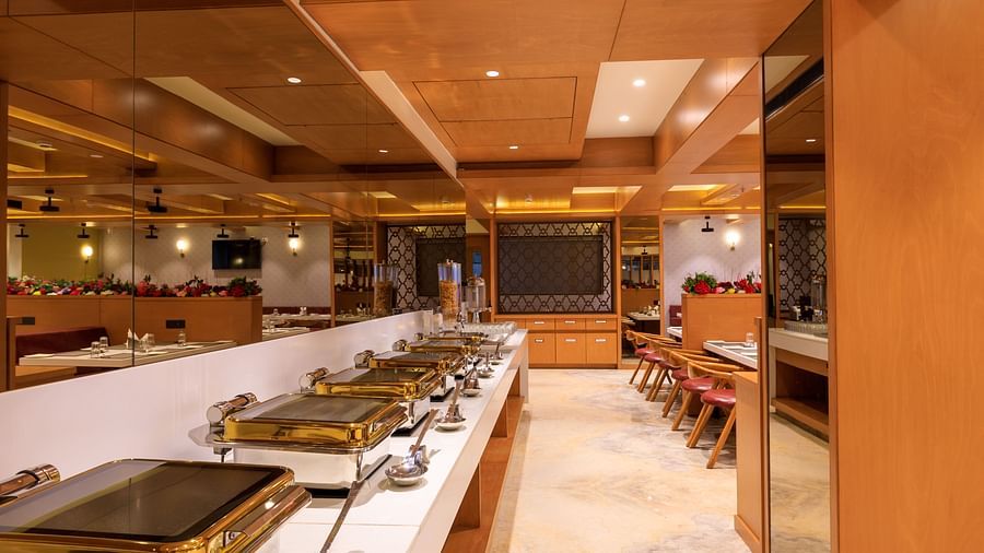 A brightly lit buffet area at Lords Eco Inn Apple Gate features multiple chafing dishes, ready to serve meals.