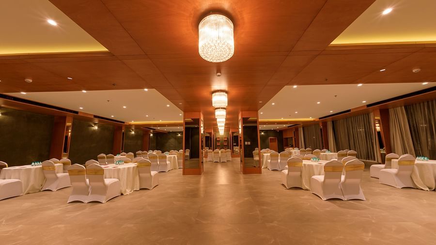 A large, warmly lit Chancellor Hall at Lords Eco Inn Apple Gate is set up with round tables and chairs, ready for an event.