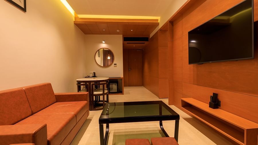 A warmly lit suite at Lords Eco Inn Apple Gate features orange sofas, a black coffee table, a wall-mounted TV, and a small dining area.