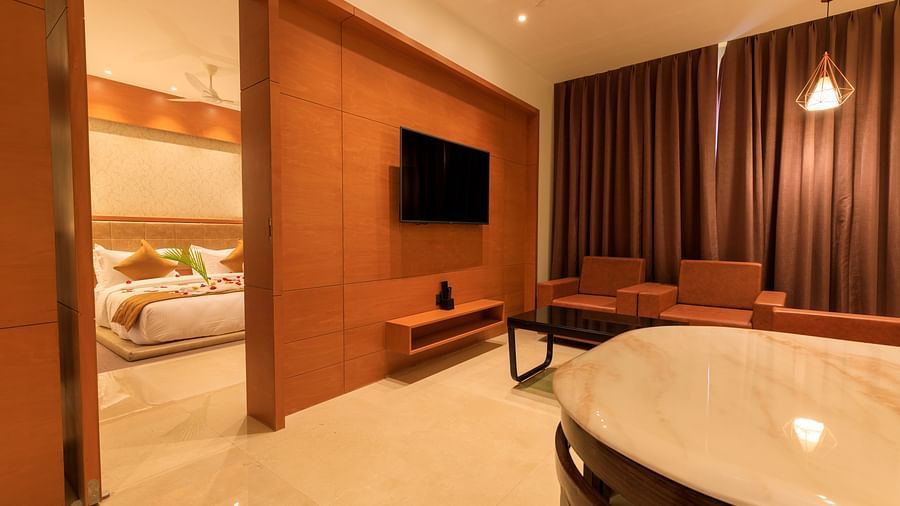 A warmly lit suite at Lords Eco Inn Apple Gate shows a lounge area with orange seating and a glimpse into a decorated bedroom.
