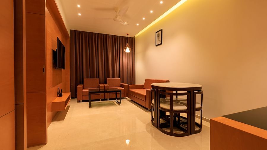A warmly lit suite at Lords Eco Inn Apple Gate features orange sofas, armchairs, a coffee table, and a small dining set.