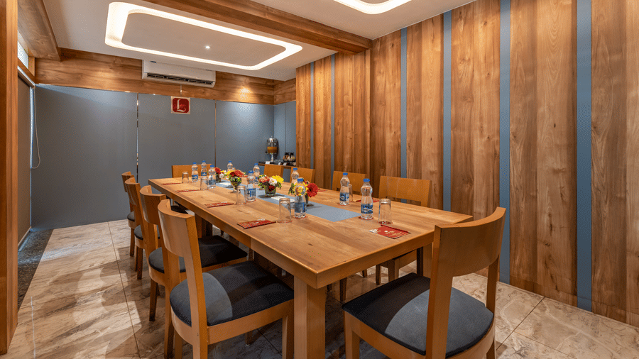 A modern Board Room in  Lords Eco Inn with a long wooden table, wood-paneled walls, and a large window.