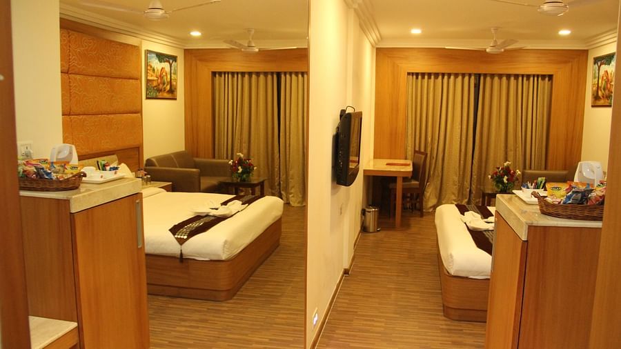 Spacious hotel room with sitting area and double bed, warmly lit