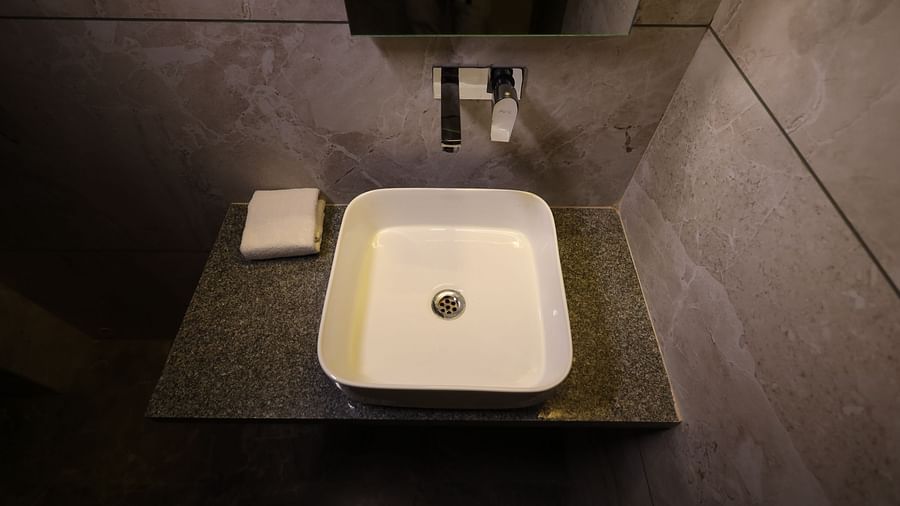 A bathroom sink with a modern faucet and a bar of soap sits on a countertop - Lords Eco Inn Navsari.