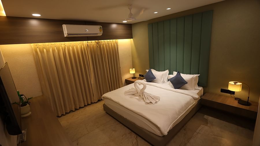 A hotel room in Bengaluru, possibly at Lords Eco Inn, includes a bed with decorative towels, nightstands with lamps, and curtains - Lords Eco Inn Navsari.