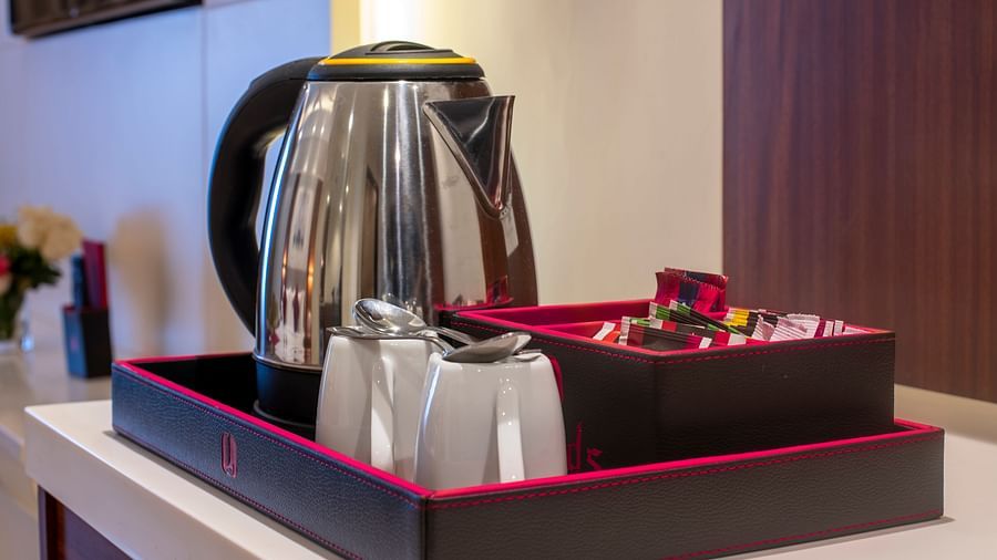 Close-up of in-room tea and coffee kit with kettle, cups, and condiments on a tray - Lords Eco Inn Shapar Rajkot