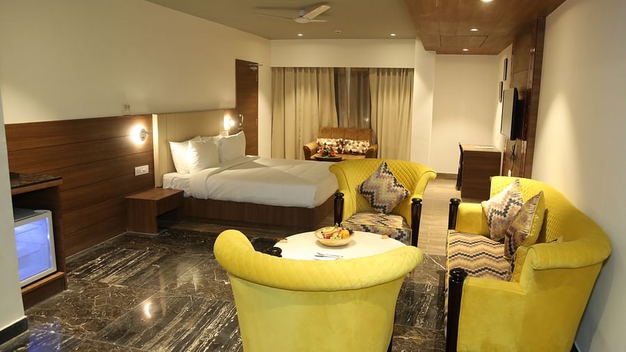 A hotel room at Lords Inn Udaipur showcases a bed, bright yellow armchairs around a small table, and modern interiors.