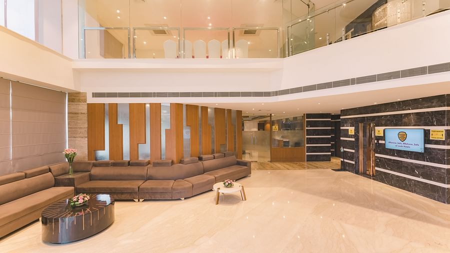 The expansive and modern lobby of Lords Inn Udaipur offers ample seating and a view of the upper level through glass railings.