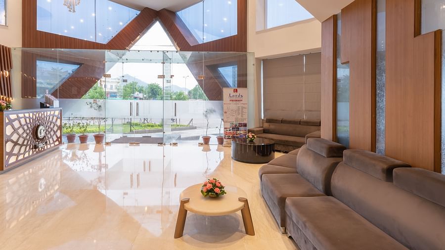 The spacious lobby of Lords Inn Udaipur showcases modern design with large windows, comfortable seating, and a polished floor.