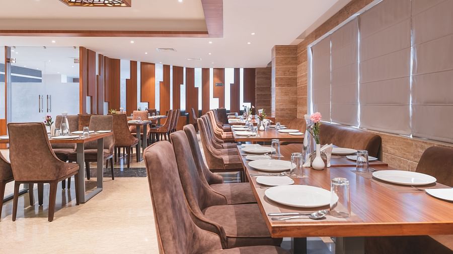The elegant Blue Coriander Restaurant at Lords Inn Udaipur is set with neatly arranged tables, chairs, and place settings.