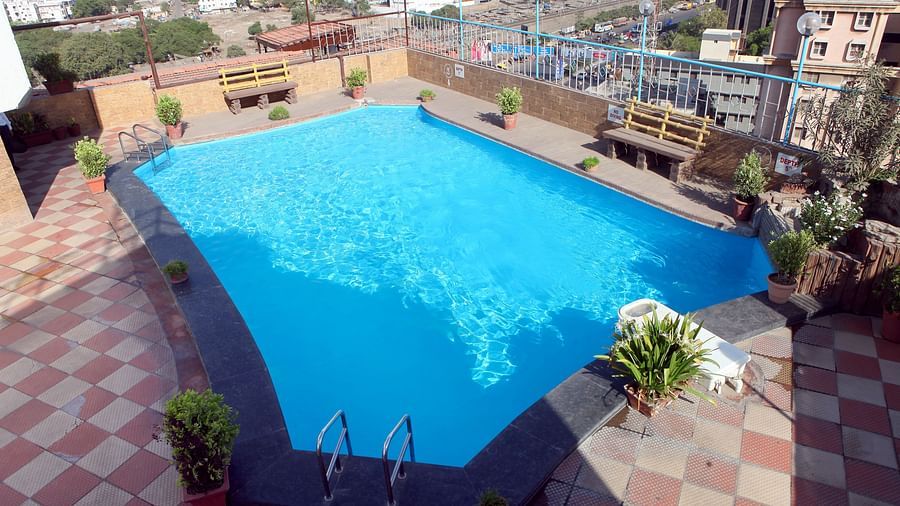 An outdoor swimming pool with surrounding cityscape at Lords Plaza Surat.