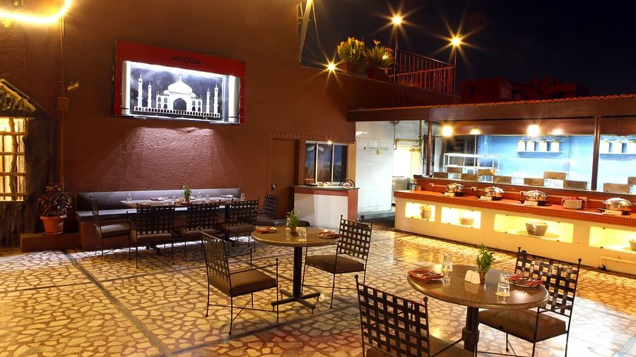 A warmly lit dining or lounge area with tables and chairs at Lords Plaza Surat.