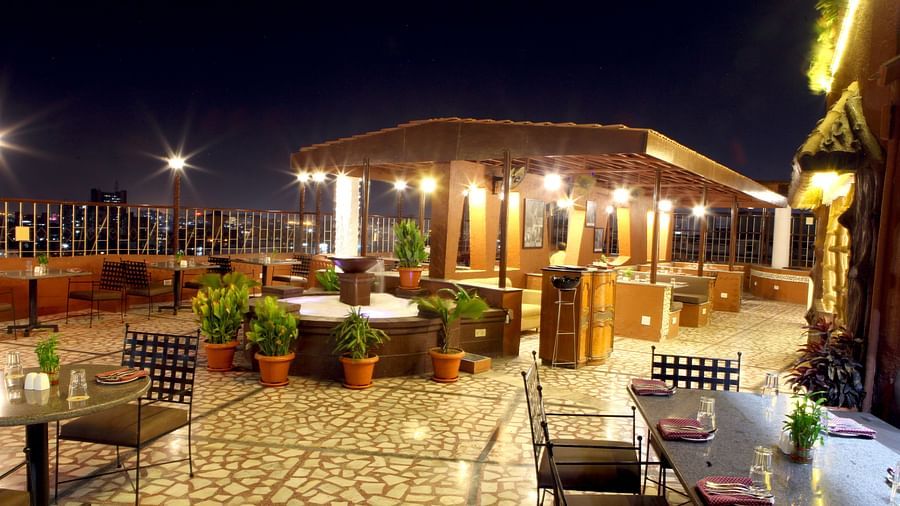 An outdoor seating area with covered structures at night at Lords Plaza Surat.