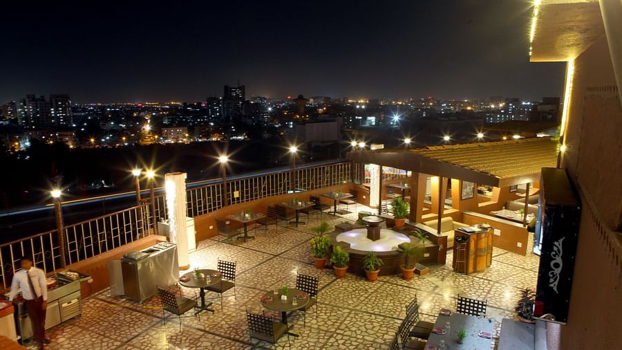 An outdoor seating area with city lights visible at night at Lords Plaza Surat.