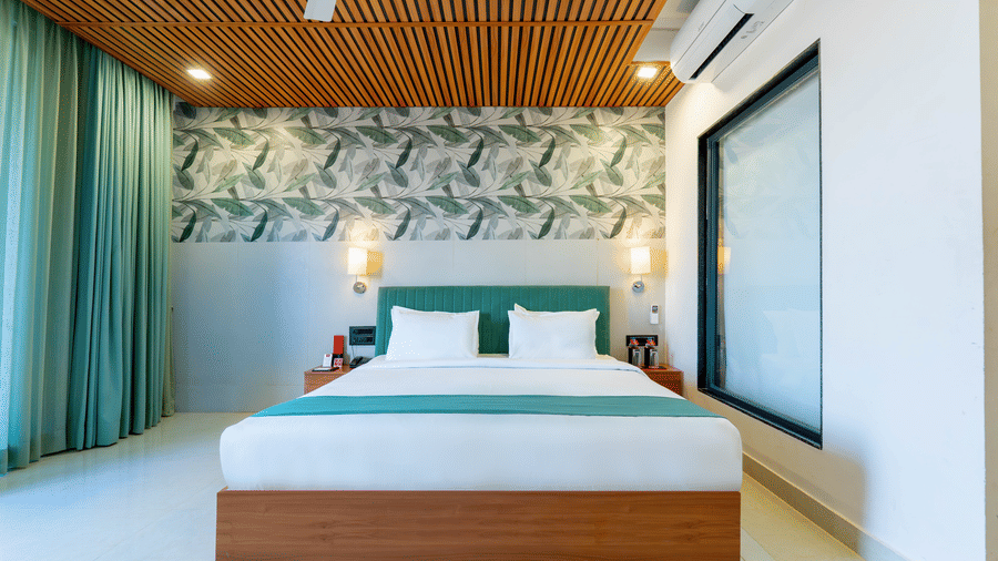 Minimalist bedroom at Lords SKD Resort, Salangpur, with a wooden-slat ceiling and tropical leaf wallpaper.