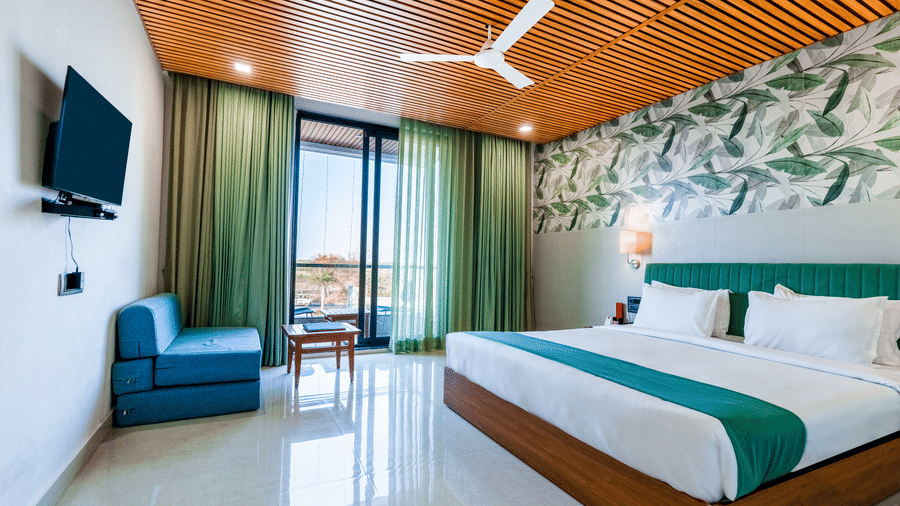 Large guest room at Lords SKD Resort, Salangpur, featuring a blue sofa bed, ceiling fan, and balcony view.