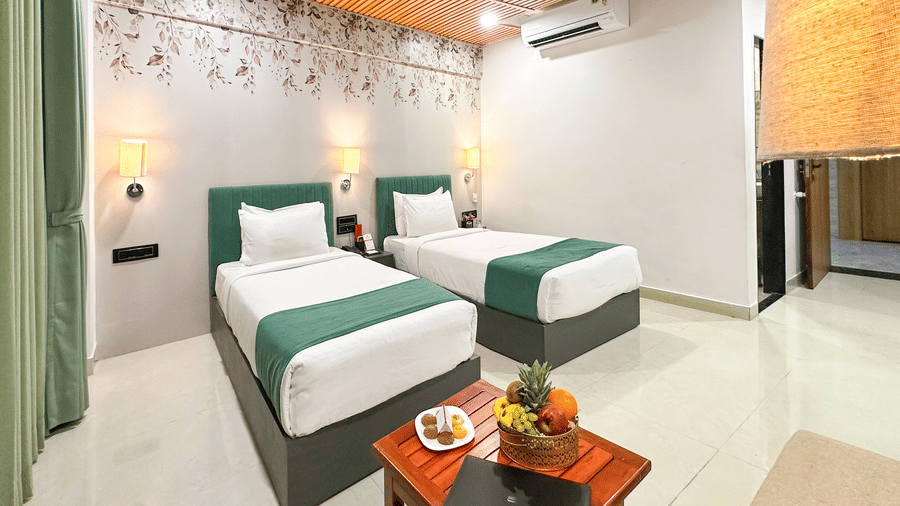 Stylish twin bedroom at Lords SKD Resort, Salangpur, featuring teal headboards, wooden ceilings, and a fresh fruit platter.