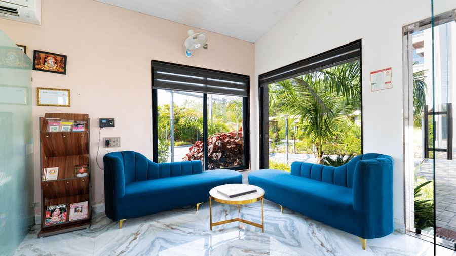 Bright lounge seating area with blue sofas and large windows at Lords SKD Resort, Salangpur.