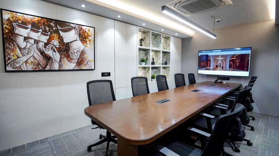 The boardroom at M2 Square by Monday Premium featuring a long wooden table along with an abstract painting hung on the wall.